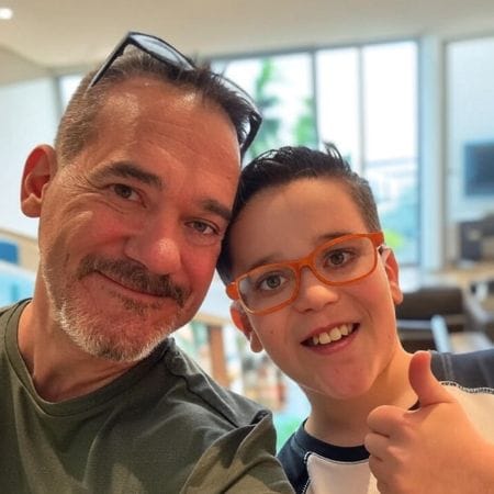 glenn A man and a smiling boy with glasses, both full of joy, take a selfie; the boy gives a thumbs up, capturing a cheerful moment for Ceemi Agency.